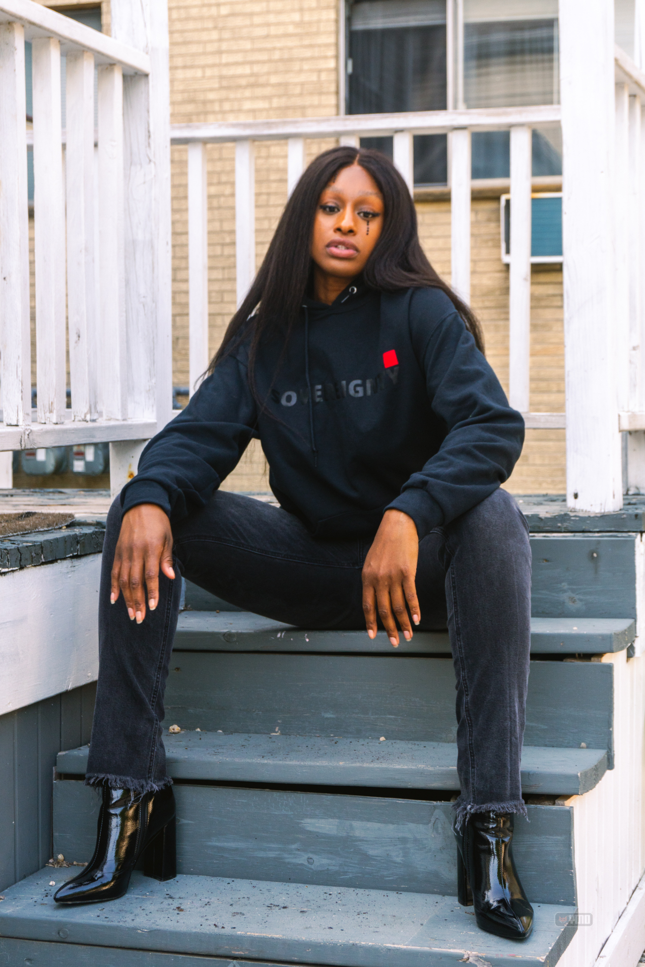 Model in a Sovereignty hoodie seated on a Milwaukee porch stoop