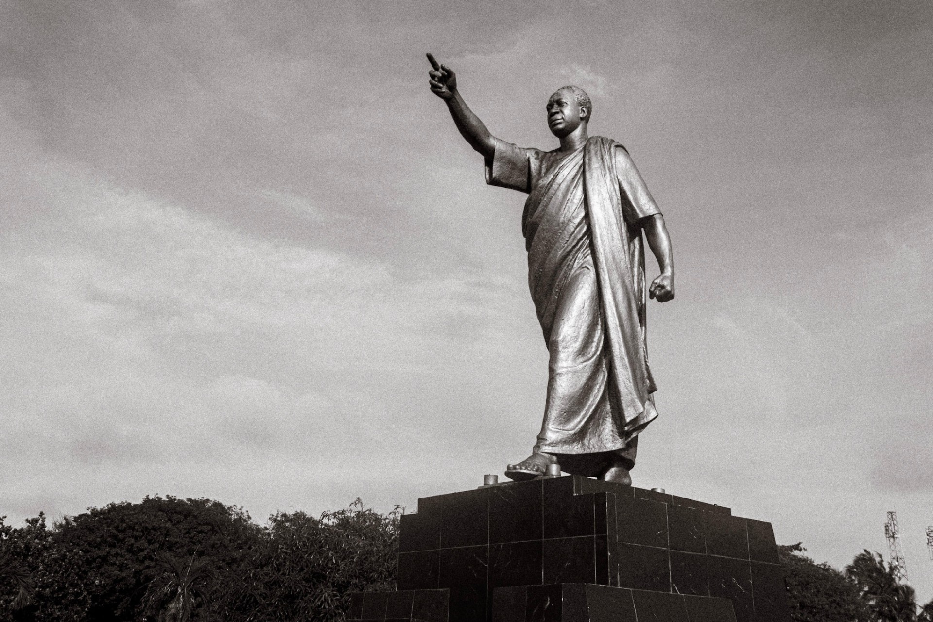 Bronze statue of Kwame Nkrumah with arm raised against the sky