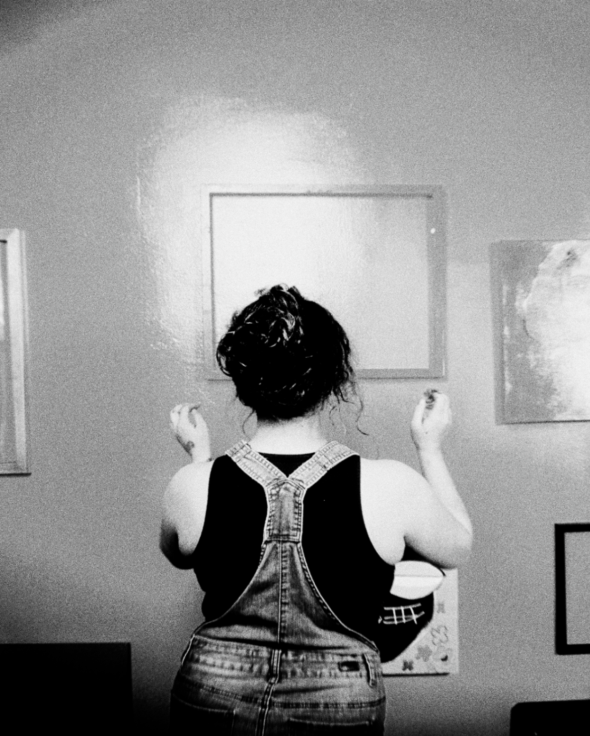 Person hanging framed art on a wall