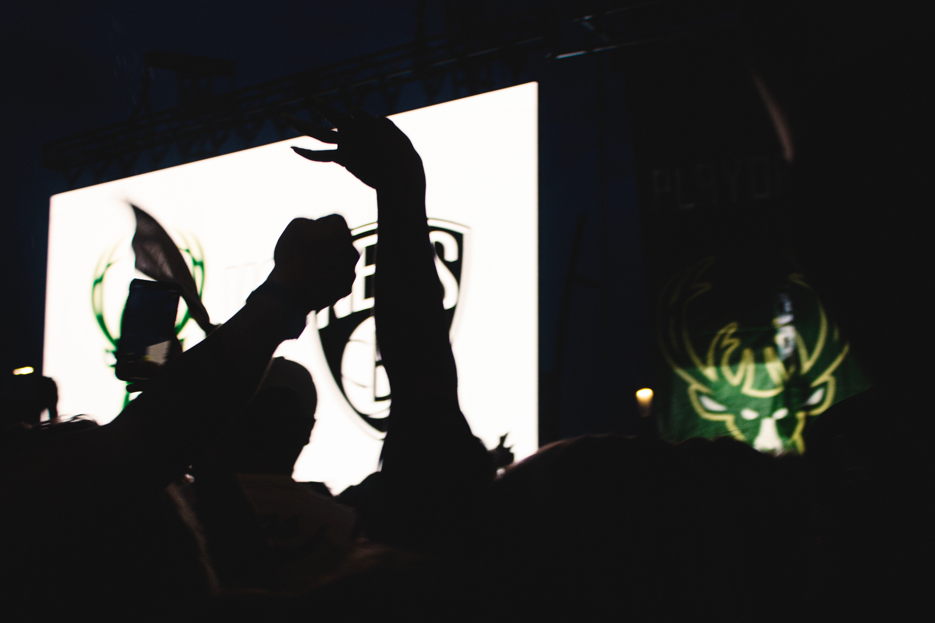 Silhouetted arms raised against the Bucks logo