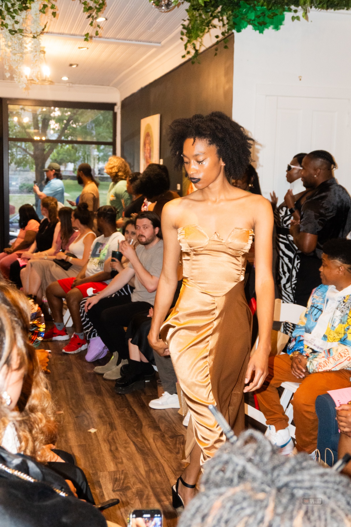 Model in a champagne satin bustier gown at the La Gente Art Gallery show