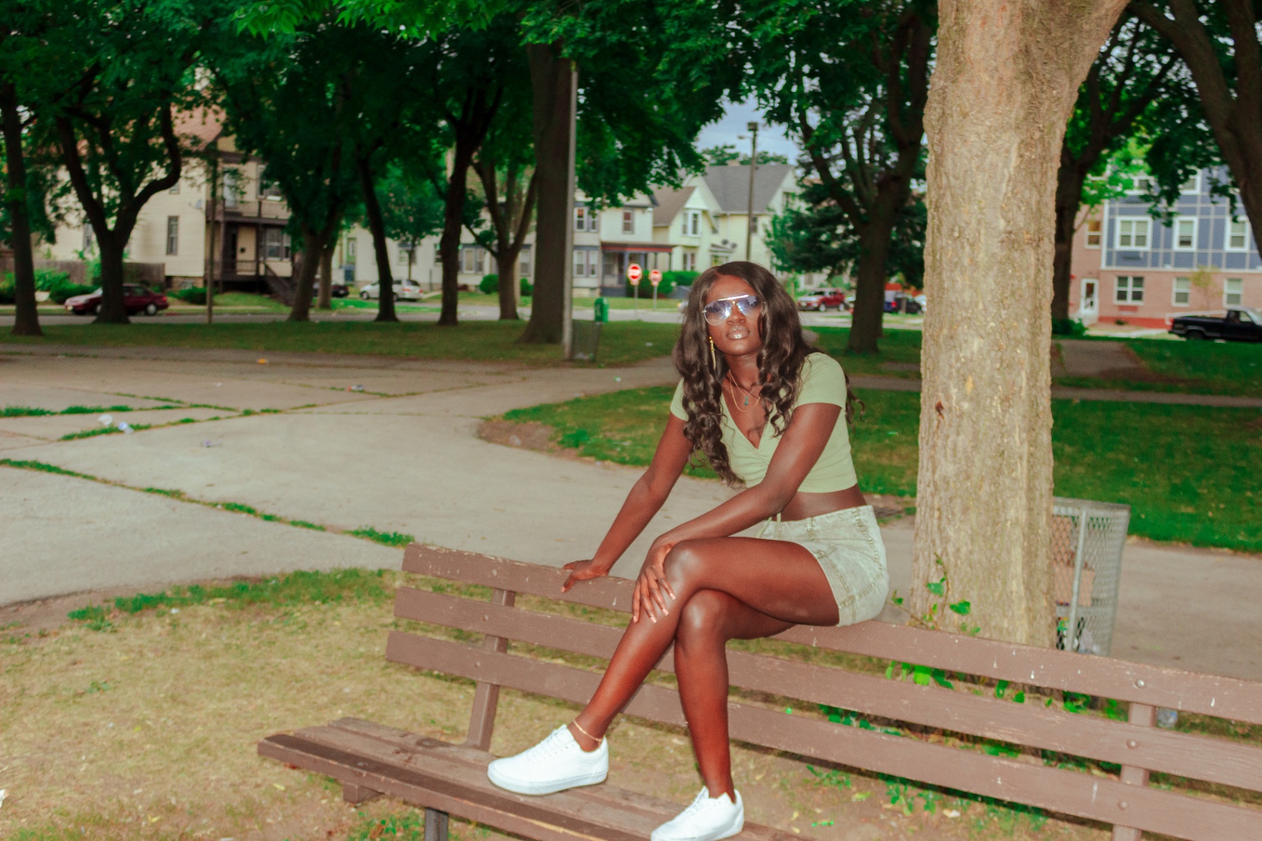 Full portrait of a woman on a park bench with Milwaukee neighborhood behind