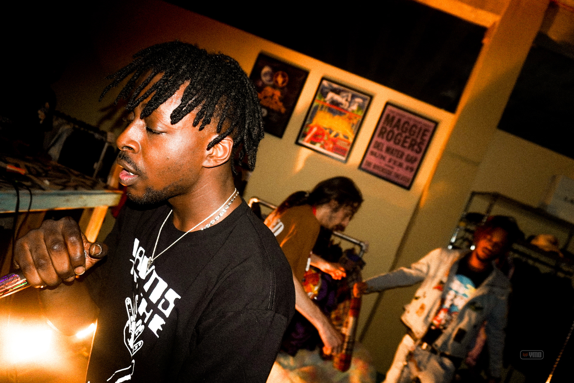Artist in a green room lit by warm tungsten with tour posters behind