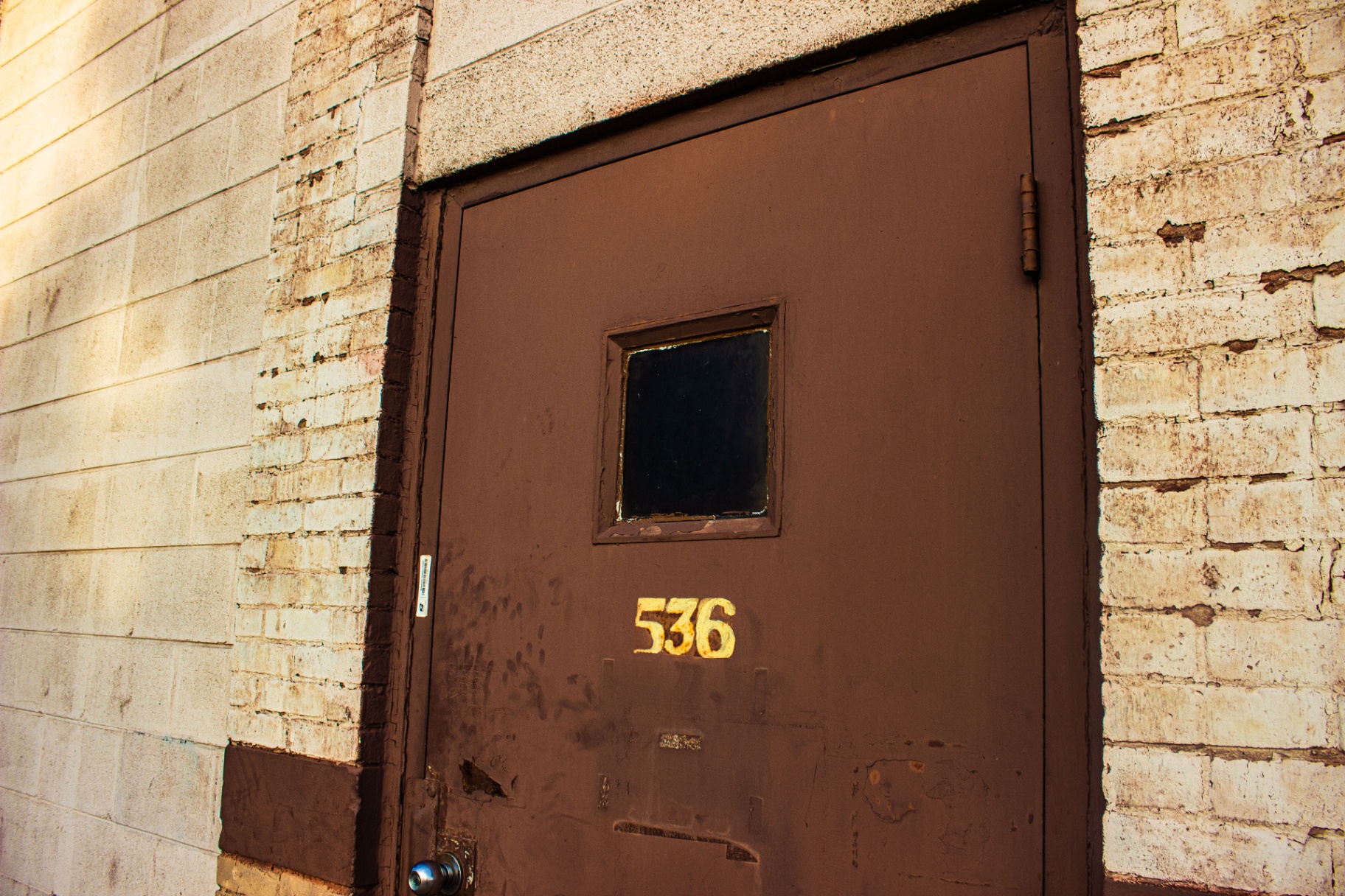 Brown steel service door numbered 536 on a painted brick wall