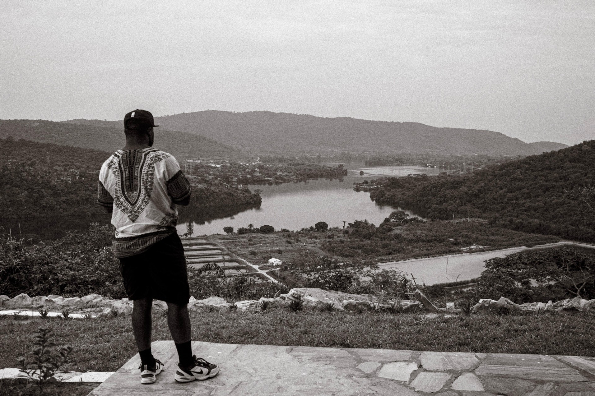 Man in a dashiki looking out over the Volta River from a hillside