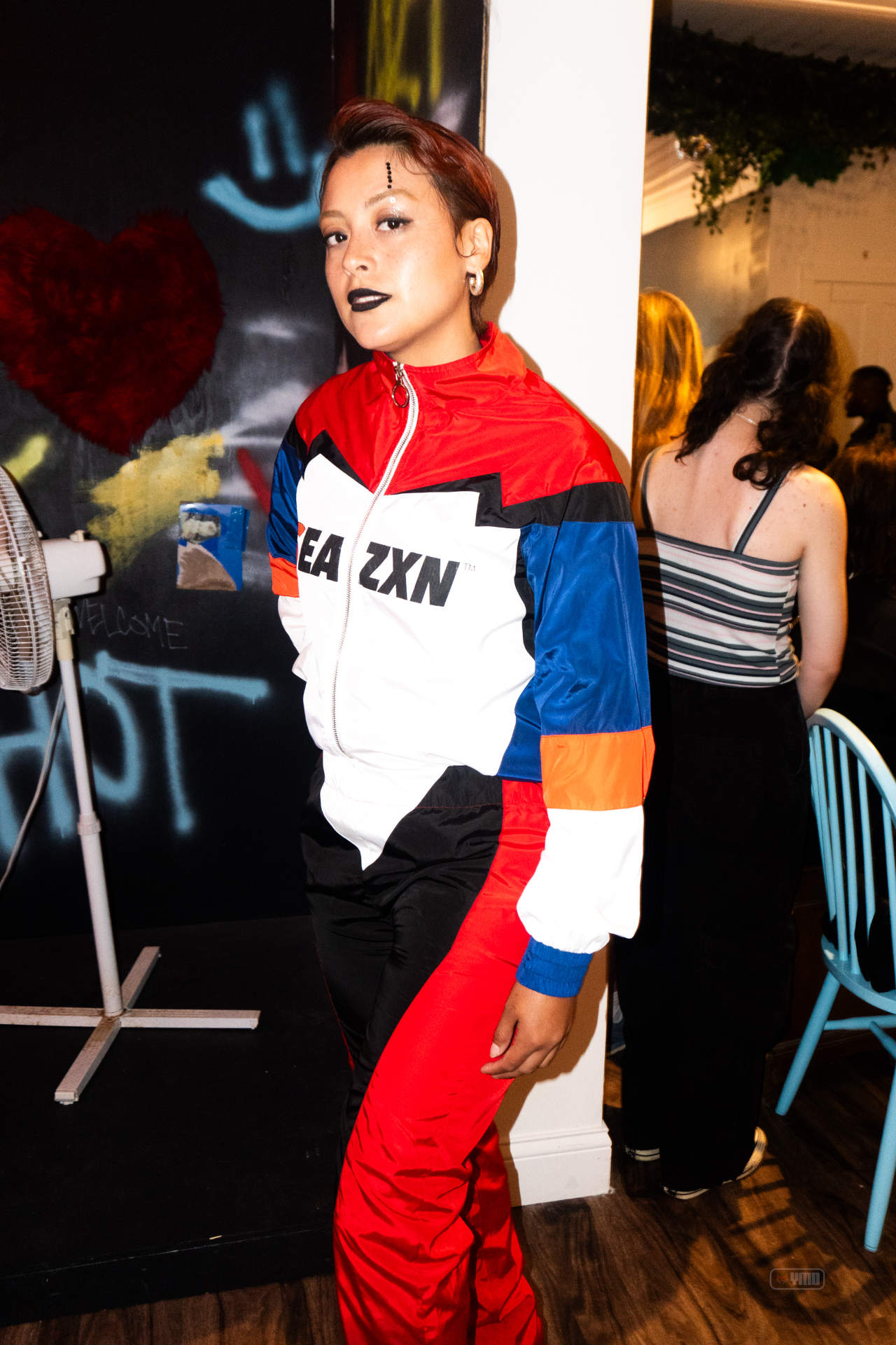 Model in a red white and blue EA ZXN tracksuit against graffiti