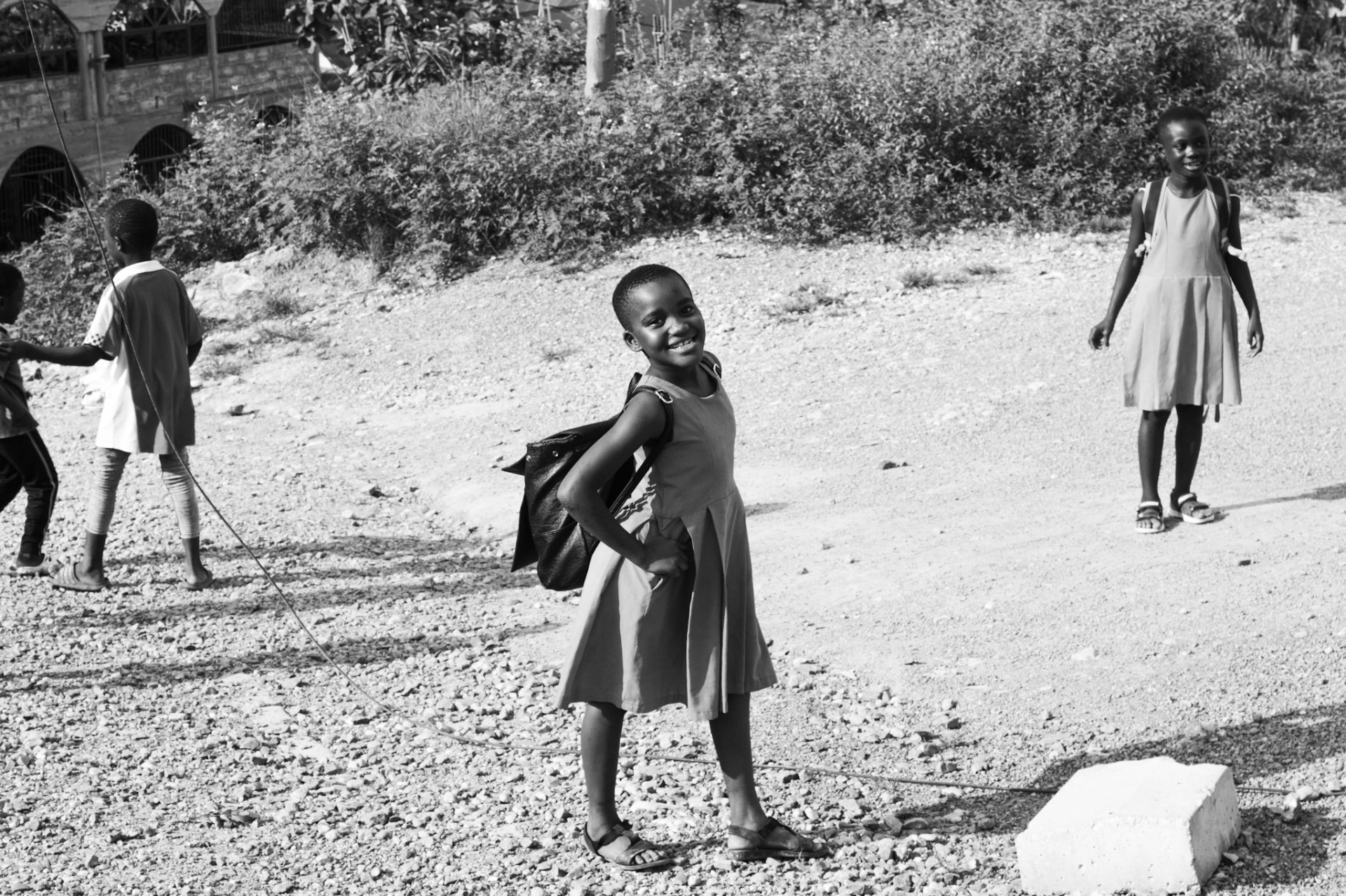 Ghanaian schoolgirl smiling on a gravel path with classmates