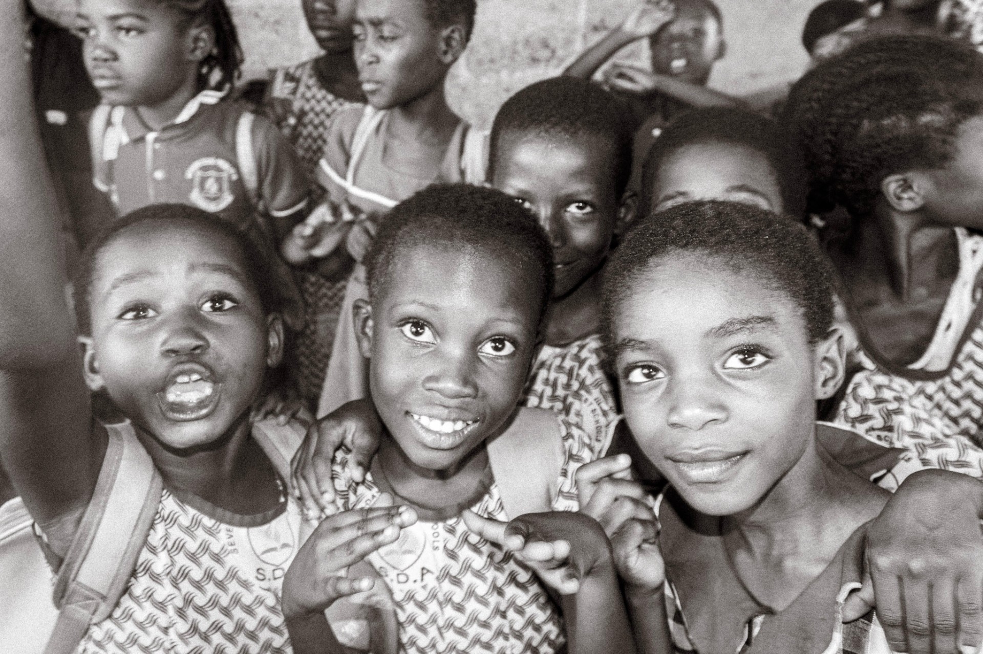 Three Ghanaian schoolchildren in uniform smiling at the camera